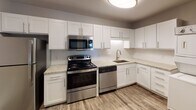 Located at 524 Bramlet Rd. in Charlotte, NC, this single-floor unit offers a thoughtfully updated interior with a cohesive modern aesthetic throughout. The living area makes a striking impression with a painted dark brick accent wall, hardwood-style flooring, and a ceiling fan, creating a comfortable and stylish setting. A sliding glass door brings in natural light and provides outdoor access.

The kitchen is well-appointed with crisp white shaker-style cabinetry, light granite countertops, a white subway tile backsplash, and a full suite of stainless steel appliances including a range, microwave, dishwasher, and refrigerator. The hardwood-style flooring continues seamlessly throughout the main living and kitchen areas.

Multiple bedrooms are carpeted and feature ceiling fans, natural light from windows with blinds, and generous closet space, including double closets in at least one bedroom. The neutral gray walls provide a versatile backdrop throughout.

The bathroom is finished with a gray vanity, granite countertop, large framed mirror, and a tub-shower combination with white subway tile surround. Wood-look flooring carries into the bathroom, tying the space together with a consistent, updated look.