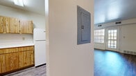 This one-bedroom, one-bathroom unit offers a straightforward and efficient single-floor layout designed to maximize functionality. The living room provides an open, comfortable space featuring wood-look hard-surface flooring and a large window that allows natural light to fill the room, creating a bright and welcoming atmosphere. A hallway connects the main living areas to the private spaces and includes a built-in electrical panel access point. The kitchen is positioned off the main corridor and features warm-toned wooden cabinetry, a white electric range, a refrigerator, and a sink — all compactly arranged for practical use. The kitchen also features wood-look flooring that complements the rest of the unit. The bedroom is a well-sized private retreat with soft carpeting, a sliding-door closet with built-in shelving, and a multi-pane window that invites outdoor views and natural light. The bathroom is clean and simply appointed, featuring a full tiled tub-and-shower combination, a toilet, and towel bars. Throughout the unit, the neutral color palette and functional finishes contribute to a cohesive, low-maintenance living environment suited for everyday comfort.
