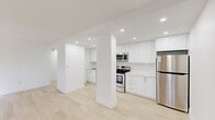 Located at 150 Allan St in Oakville, Ontario, this single-floor unit offers a clean, contemporary interior defined by a bright, neutral palette and light-toned hardwood-style flooring that runs throughout the entire space. The open layout connects the living areas seamlessly, creating a cohesive and functional flow.

The living area is a standout feature, with floor-to-ceiling sliding glass doors opening onto a private balcony that overlooks mature trees, allowing abundant natural light and greenery views to fill the space. An additional window further enhances the connection to the outdoors.

The kitchen has been fully renovated to a modern standard, showcasing high-gloss white cabinetry extending to the ceiling, stainless steel appliances including a refrigerator, electric range, built-in microwave, and dishwasher, complemented by recessed pot lighting. A structural column adds an architectural element to this area.

The bedrooms are well-proportioned, each benefiting from natural light through windows with vertical blinds and views of the surrounding greenery. One bedroom features a mirrored closet. A full bathroom with a shower-tub combination is accessible from the main living area. The overall ambiance is clean, bright, and move-in ready.