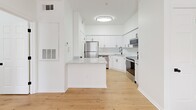 Located at 8050 Gables Commons Dr in Orlando, FL, this thoughtfully designed one-bedroom, one-bathroom residence offers a clean, modern aesthetic throughout its single-floor layout. Light natural wood-tone flooring flows seamlessly through every room, creating a warm and cohesive atmosphere.

The kitchen is a standout feature, outfitted with bright white shaker-style cabinetry, a classic subway tile backsplash, stone countertops, and a full suite of stainless steel appliances including a refrigerator, electric range, over-the-range microwave, and dishwasher. A peninsula island provides additional counter space and serves as a natural divider between the kitchen and living area.

The bedroom is a comfortable, well-proportioned space bathed in natural light from large windows with blinds, and features a ceiling fan for year-round comfort. Additional windows throughout the home invite greenery views from the surrounding landscape.

The bathroom is finished with a stone-topped vanity, wood-toned flooring, matte black hardware accents, and a full soaking tub with tiled surround. A dedicated closet and in-unit laundry add everyday convenience. The overall palette of crisp whites, natural wood, and black accents gives this residence a clean, contemporary feel.