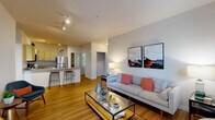 This thoughtfully designed one-bedroom, one-bathroom residence offers an efficient and comfortable single-floor layout. The open-concept living and kitchen area forms the heart of the home, where warm hardwood-style flooring flows seamlessly throughout. The living room is bright and inviting, featuring large windows that frame views of surrounding greenery, filling the space with natural light. A dedicated dining nook sits adjacent to the living area, accommodating a bistro-style table and chairs beneath sun-lit windows.

The kitchen is well-equipped with light maple cabinetry, stainless steel appliances including a refrigerator, range, and built-in microwave, and a double-basin sink. A peninsula with a breakfast bar provides additional prep space and casual seating for two. Track lighting overhead ensures excellent task illumination.

The bedroom is a comfortable retreat with plush carpeting, a window with lush outdoor views, and a ceiling fan. A dedicated closet provides practical storage. The full bathroom features light maple cabinetry, a single-basin vanity with stone-style countertop, and a shower-tub combination. A separate laundry room with a full-size washer and dryer with overhead shelving adds everyday convenience to this well-rounded home.