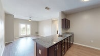 Located at 9000 Balch St in Fort Worth, TX, this single-story, 3-bedroom, 2-bathroom home offers a well-designed layout with a cohesive, modern aesthetic throughout. Light-toned luxury vinyl plank flooring flows seamlessly across the main living areas, complemented by neutral warm-gray walls and crisp white trim.

The open-concept kitchen and dining area serves as the heart of the home, featuring a peninsula with rich dark espresso cabinetry, granite countertops, an undermount sink, and stainless steel appliances including a refrigerator. Upper cabinets provide ample storage, while the peninsula creates a natural divide from the living area. The spacious living room is brightened by a ceiling fan and French doors that open directly onto a private patio, allowing natural light to pour in.

Each of the three bedrooms offers its own ceiling fan, generous closet space, and windows with views to the outdoors. The primary bedroom provides a comfortable, well-proportioned retreat. Both bathrooms are finished consistently with granite-topped dark vanities, tile flooring, and full tub-shower combinations. Additional conveniences include a dedicated laundry area, a pantry, and an abundance of closet storage throughout. The layout is practical and efficient, making excellent use of the available space.