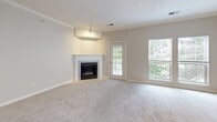 This single-floor residence offers a thoughtfully organized layout across two bedrooms and two bathrooms. The combined living and dining area serves as the heart of the home, highlighted by a fireplace framed with a clean tile surround, plush carpeting, crown molding, and a textured ceiling. Multiple windows and a glass-paneled exterior door bathe the space in natural light and provide views of surrounding greenery. The adjacent dining area features crown molding and a chandelier overhead, adding a refined touch.

The kitchen is equipped with dark espresso cabinetry, granite-style countertops, a peninsula with a built-in sink, hardwood-style flooring, and black appliances including a refrigerator, range, and microwave.

The generously sized primary bedroom includes a sliding glass door and dual windows offering tree-lined views, soft carpet, and direct access to an en-suite bathroom fitted with a dark-vanity and a tub-shower combination. The second bedroom is carpeted and well-lit. The second bathroom features a tiled tub-shower surround. Additional conveniences include two closets, a hallway, and an in-unit laundry area.