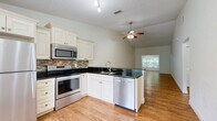 Located at 5223 Hunters Ridge Drive in New Port Richey, FL, this single-story 2-bedroom, 2-bathroom home offers a well-organized layout with a consistent design aesthetic throughout. The open-concept kitchen and living area serves as the heart of the home, featuring white raised-panel cabinetry, dark granite countertops, a mosaic tile backsplash, and a full suite of stainless steel appliances including a refrigerator, range, microwave, and dishwasher. A breakfast bar peninsula connects the kitchen to the living space, which is illuminated by a ceiling fan with light kit and benefits from natural light through vertical-blind-covered windows with lush outdoor views. Warm wood-look laminate flooring runs throughout the home, adding continuity and warmth. The primary bedroom is a comfortable, well-proportioned retreat featuring a walk-in closet with wire shelving and an en-suite bathroom with a glass-enclosed shower, granite-topped vanity, and tile flooring. The second bedroom also features a ceiling fan, a closet, and a window with greenery views. The second bathroom offers a full tub-shower combo, a granite-topped vanity, and tile flooring. A dedicated hallway closet provides additional storage. Ceiling fans are installed throughout for year-round comfort.