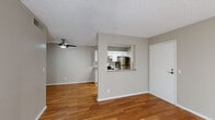 This single-floor residence offers a clean, functional layout highlighted by warm hardwood-style flooring that flows throughout the main living areas. The open-concept living and dining space is anchored by a ceiling fan and features a distinctive pass-through window connecting seamlessly to the kitchen, creating an open and communicative feel between the two areas. A sliding glass door with vertical blinds fills the living area with generous natural light and provides access to the outdoors.

The kitchen is well-appointed with white shaker-style cabinetry, subway tile backsplash, laminate countertops, and a full suite of stainless steel appliances including a refrigerator, electric range, and dishwasher. Light tile flooring keeps the kitchen bright and easy to maintain. A dedicated laundry area is accessible directly from the kitchen.

The bedrooms are comfortable and naturally lit, each featuring hardwood-style flooring and window blinds for privacy. The bathroom includes a wide vanity with white cabinetry, a vessel sink, a large mirror, and contemporary light fixtures, all set on neutral tile flooring. Textured ceilings are present throughout, and the neutral gray wall tones lend a cohesive, modern aesthetic across the entire space.