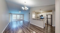 Located at 299 Leydecker Rd in Buffalo, NY, this well-appointed single-floor, 3-bedroom, 2-bathroom home offers a thoughtfully designed open-concept layout that maximizes livability and flow. The combined kitchen and living area serves as the heart of the home, featuring rich hardwood-style flooring, vaulted ceilings, and an elegant chandelier that adds a refined touch. The kitchen is highlighted by white cabinetry, granite countertops, stainless steel appliances including a refrigerator, microwave, and range, and a peninsula with bar seating illuminated by stylish pendant lighting — ideal for casual dining or entertaining. The living area is bright and open, benefiting from large windows that invite natural light. The three bedrooms offer comfortable proportions, with plush carpeting and windows overlooking the surrounding neighborhood. The spacious primary bedroom provides a generous personal retreat. Both bathrooms are finished with white cabinetry, granite countertops, undermount sinks, and brushed nickel fixtures, lending a clean, modern aesthetic. A dedicated in-unit laundry room with full-size washer and dryer adds everyday convenience. Neutral tones and consistent finishes throughout create a cohesive, move-in-ready atmosphere.