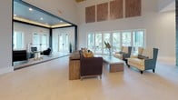 This expansive single-floor clubhouse is designed to impress, blending contemporary aesthetics with warm, inviting details across a variety of gathering spaces. The grand main lounge anchors the facility with soaring ceilings, a striking gold-toned ceiling feature, large-format tile flooring laid in a herringbone pattern, and dramatic pendant lighting. A floor-to-ceiling dark stone accent wall adds architectural depth, while large glass doors and windows flood the space with natural light and provide views of lush outdoor greenery.

Multiple distinct seating areas flow seamlessly from one to the next. A dedicated lounge room features exposed wood beam ceilings, geometric gold chandeliers, and ample natural light through large windows. A moodier sitting nook showcases a bold herringbone-patterned wood wall panel and dark, sophisticated furnishings. A media lounge offers a built-in entertainment center with open shelving and curated décor.

A fully equipped catering kitchen stands out with light wood cabinetry, stone countertops, stainless steel appliances including double wall ovens and a commercial-grade refrigerator, and a central island. A stylish coffee and refreshment bar nearby features mosaic tile backsplash, granite countertops, and custom cabinetry. Together, these spaces create a well-appointed, multifunctional facility suited for a range of social and community events.