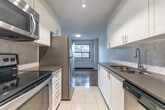 This 760 square foot apartment in Burlington, Ontario, offers a harmonious blend of urban living and natural scenery. The space is efficiently designed with two bedrooms and an open-concept living area. The standout feature is the beautiful parquet flooring that runs throughout, adding warmth and character to each room.

Large windows dominate the living areas, flooding the space with natural light and providing picturesque views of the surrounding greenery and cityscape. The primary bedroom, measuring 150 square feet, offers ample space for rest and relaxation.

The kitchen is a highlight, featuring sleek white cabinetry, modern appliances, and a functional galley layout. It seamlessly integrates with the living area, perfect for entertaining or casual dining. The apartment also boasts a sliding mirrored closet door, maximizing space and light.

Baseboard heating ensures comfort throughout the seasons, while the neutral color palette provides a blank canvas for personal style. The balcony, accessible through sliding glass doors, extends the living space outdoors, offering a private nook for fresh air and urban views.

Located at 2077 Prospect St, this apartment combines the convenience of city living with the tranquility of a suburban setting, making it an ideal residence for those seeking a balanced lifestyle in Burlington.
