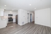 Located at 1704 Hornblend St in San Diego's Pacific Beach neighborhood, this 2-bedroom, 2-bathroom unit offers a clean, modern design throughout its well-utilized single-floor layout. Light wood-style flooring flows consistently through every room, complementing the crisp white walls and creating a bright, cohesive aesthetic.

The kitchen is a standout feature, outfitted with white shaker cabinetry, light quartz countertops, a stainless steel sink, and a full suite of stainless steel appliances including a refrigerator, range, microwave, and dishwasher. Recessed lighting adds a polished finish to this functional space.

The combined dining and living area provides an open, comfortable gathering space with recessed lighting. Both bedrooms are well-proportioned and filled with natural light; the primary bedroom includes sliding glass door access to a private balcony, while the second bedroom features a window with vertical blinds and a built-in closet with sliding doors.

The two bathrooms reflect the unit's modern sensibility: one features a sleek frameless glass walk-in shower with subway tile surround, while the second offers a full shower-tub combo. Both include white vanities and wood-style flooring. Additional conveniences include in-unit laundry, a utility room, and ample closet storage throughout.