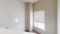 Located at 312 W Elm Ave in Stillwater, Oklahoma, this two-story unit offers a well-utilized layout across two distinct levels. The main floor, which comprises the larger portion of the total footprint, features an open-concept living area that flows into a functional kitchen equipped with dark appliances including a refrigerator and range. A hallway leads to the entrance, and a bathroom on this level includes a vanity with a dark cabinet, toilet, and a tub/shower combination, all finished with hardwood-style flooring that runs consistently throughout the space.

A staircase positioned along one wall connects to the upper level, which serves as a loft-style secondary space. This upper area benefits from elevated ceilings and an open railing that overlooks the floor below, enhancing the sense of vertical openness. Natural light is introduced through a window fitted with horizontal blinds, brightening the otherwise neutral, light-toned walls.

Throughout both levels, the design is clean and minimal, with white walls, white trim, and warm wood-toned flooring creating a cohesive and practical aesthetic. HVAC vents are present on the upper level, ensuring climate comfort. The overall layout is efficient, making thoughtful use of its compact footprint across two floors.