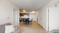 Located at 10420 E Burnside St in Portland, Oregon, this single-floor, three-bedroom, one-bathroom residence offers a thoughtfully arranged layout with modern finishes throughout. The open-concept kitchen and dining area serves as the heart of the home, featuring warm wood-toned cabinetry, stainless steel appliances including a refrigerator, range, and microwave, light countertops, and durable hardwood-style flooring. A dining table positioned adjacent to the kitchen makes everyday meals and entertaining convenient. The living room receives generous natural light through a large window with vertical blinds, and is finished with plush carpeting that adds warmth and comfort. Each of the three bedrooms is carpeted and naturally lit, with vertical blinds on the windows. The primary bedroom includes a spacious walk-in closet outfitted with wire shelving and hanging rods for ample storage. The full bathroom features hardwood-style flooring, a wood-toned vanity with a white countertop, and a shower-tub combination. Clean white walls and consistent flush-mount lighting carry throughout the residence, creating a bright, cohesive aesthetic. The overall design is clean and functional, suited for comfortable everyday living in Portland's east side.