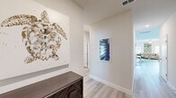 This thoughtfully designed single-story home offers a comfortable and functional layout across two bedrooms, four bathrooms, and a dedicated office space. The open-concept living, dining, and kitchen area serves as the heart of the home, where light wood-look flooring flows seamlessly underfoot. The kitchen features gray cabinetry, granite countertops, stainless steel appliances, and a central island with bar seating — ideal for both cooking and casual entertaining. The dining area is bathed in natural light from a large sliding glass door that opens to an outdoor patio, providing easy indoor-outdoor access. The living room offers a bright, welcoming atmosphere with dual windows and a ceiling fan overhead. The primary bedroom is a generously sized retreat with light wood flooring and access to a private en-suite bathroom featuring gray cabinetry and granite countertops. The second bedroom features plush carpeting and a window with blinds for natural light control. The dedicated office, finished with carpet and a window, provides a quiet workspace. A central hallway, accented with coastal-inspired artwork, connects the rooms with ease. With four full bathrooms, this home offers ample convenience for residents and guests alike.