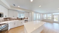 Located at 5300 N Mays St in Georgetown, TX, this well-appointed one-bedroom, one-bathroom residence offers a thoughtfully designed single-floor layout with a clean, modern aesthetic. Light wood-tone flooring runs consistently throughout the entire unit, tying each room together seamlessly.

The open-concept kitchen and living area forms the heart of the home. The kitchen is equipped with full stainless steel appliances — including a refrigerator, range, microwave, and dishwasher — paired with crisp white shaker-style cabinetry featuring black hardware, a textured tile backsplash, white quartz countertops, and a central island ideal for meal prep or casual dining. Multiple windows flood the space with natural light, while a door provides direct outdoor access from the living area.

The bedroom is a comfortable, well-lit room with a ceiling fan, a window with outdoor views, and direct access to both the bathroom and a dedicated walk-in closet. The walk-in closet offers built-in shelving, multiple hanging rods, and ample storage. The bathroom includes a tub-shower combination with tile surround and matte black fixtures, maintaining the home's cohesive modern style. Recessed lighting throughout the unit enhances the bright, airy atmosphere.