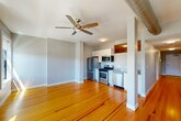 Unit 8 at 170 Pleasant St in Fall River, Massachusetts offers a thoughtfully laid-out single-floor residence with an efficient and functional design. The open-concept kitchen and living area form the heart of the unit, seamlessly blending everyday living and cooking spaces. The kitchen is equipped with stainless steel appliances — including a gas range, over-the-range microwave, dishwasher, and refrigerator — complemented by white cabinetry, granite countertops, and warm hardwood flooring that extends throughout the unit. The living area is generously sized and bathed in natural light through multiple large windows, offering views of the surrounding Fall River cityscape. Ceiling fans are installed in both the living and kitchen areas, adding to the comfort of the space. Exposed ductwork lends an industrial character to the interior. The bathroom features light tile flooring and clean, neutral finishes, with an adjacent stacked washer and dryer providing in-unit laundry convenience. Neutral gray walls throughout the space create a calm, versatile backdrop. The overall ambiance is bright, modern, and functional, making this unit a practical and comfortable urban residence in the heart of Fall River.