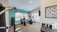 Located at 2759 Towne Blvd in Middletown, Ohio, this fitness center is a efficiently designed, single-room exercise facility that offers a well-rounded workout experience despite its compact footprint. The space is thoughtfully laid out to maximize usability, with a patterned carpet floor and a clean, contemporary aesthetic defined by neutral gray walls accented by a bold teal feature wall.

Natural light flows in generously through multiple windows fitted with horizontal blinds, offering views of the surrounding community. A full-length wall mirror visually expands the space and allows users to monitor their form during workouts. Recessed ceiling lighting ensures the room remains well-lit at all hours.

The fitness center is equipped with a solid selection of cardio machines, including a treadmill, elliptical trainer, and a recumbent exercise bike. A multi-station cable machine provides options for strength and resistance training, while a dumbbell rack supplies free weights for additional exercise variety. A flat-screen television is mounted on the wall, adding to the comfort of longer workout sessions.

A dark-countered service station with a wood-toned cabinet base sits near the entrance, offering a convenient surface for personal belongings. A coat hook rail is also mounted on the wall nearby. The room connects directly to an adjacent common area, making it an accessible and functional amenity within the broader facility.