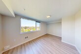 Located at 1221 NE 180th St in Shoreline, WA, this two-bedroom, one-bathroom residence offers a well-designed single-floor layout with a clean, modern aesthetic. Light wood-style luxury vinyl plank flooring runs throughout the main living areas and hallways, lending a cohesive and contemporary feel to the space.

A central hallway connects all rooms efficiently, featuring recessed lighting and sliding doors that maximize space. The spacious primary bedroom is generously sized, bathed in natural light through a large picture window that frames elevated treetop and neighborhood views — a standout feature of the home. The second bedroom is similarly appointed, with its own large window offering comparable outdoor views and ample room for flexible use.

The bathroom is finished in a clean, minimalist style with light flooring, white walls, a dark-toned vanity with a sink, and accessibility-friendly grab bars. A dedicated closet provides practical storage, complete with wire shelving and carpeted flooring. The second bedroom also features carpet, offering a softer feel distinct from the rest of the unit.

Throughout the space, neutral warm-toned walls, recessed and flush-mount lighting, and consistent finishes create a bright and welcoming ambiance. The overall layout is functional and thoughtfully organized, making efficient use of the available square footage.