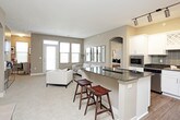 This single-floor residence offers a thoughtfully designed layout that balances comfort and functionality. The kitchen is a standout feature, showcasing white shaker-style cabinetry, dark granite countertops, a tiled backsplash, stainless steel appliances including a side-by-side refrigerator with ice and water dispenser, and a breakfast bar with seating — all set atop warm hardwood-style flooring with track lighting overhead. The living room is bright and welcoming, featuring plush carpeting, a patio door with transom windows that invite abundant natural light, and direct access to an outdoor balcony. Two well-proportioned bedrooms offer carpeted floors, ceiling fans, and large windows with blinds that filter natural light. The primary bathroom features a granite-topped white vanity, wood-look tile flooring, a walk-in glass shower, and a soaking tub, with a direct connection to the bedroom. The secondary bathroom mirrors the same refined finishes. A dedicated in-unit laundry room houses a full-size washer and dryer with overhead cabinetry for added storage. Throughout the residence, a neutral taupe and gray color palette creates a cohesive, modern ambiance.