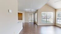 This 680-square-foot, single-floor apartment offers 2 bedrooms and 1 bathroom with a thoughtful layout and modern finishes throughout. The living room is a standout space, featuring dramatic vaulted ceilings, a ceiling fan, a slate-tiled fireplace, and large windows that flood the room with natural light and offer outdoor views. Dark hardwood-style flooring runs consistently through the living areas and bedrooms, adding warmth and cohesion.

The combined kitchen and living area is efficiently designed, featuring a peninsula with a built-in sink, stainless steel appliances including a refrigerator, microwave, and range, white cabinetry, and light tile flooring. The open layout connects the kitchen seamlessly to the living space.

The primary bedroom measures 140 square feet and includes a ceiling fan and a large double-door closet. The second bedroom also features dark hardwood-style floors, a ceiling fan, a closet, and a window for natural light. Both bedrooms offer a clean, neutral aesthetic with beige walls and white trim.

The bathroom is finished with light tile flooring, a tub-shower combo with tiled surround, and a towel bar, maintaining the unit's clean and functional design. Overall, the apartment presents a bright, well-maintained living environment.
