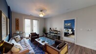 Located at 2785 Polo Club Blvd in Lexington, Kentucky, this single-floor residence offers a thoughtfully designed layout with a bold, contemporary aesthetic throughout. The open-concept kitchen and living area serves as the heart of the home, featuring dark cabinetry, white quartz countertops, stainless steel appliances including a refrigerator, range, microwave, and dishwasher, all set against a striking cobalt blue accent wall. Pendant lighting illuminates the kitchen peninsula, which flows naturally into the living room. The living area is finished with rich hardwood-style flooring and direct access to a private exterior door that invites natural light. The primary bedroom is appointed with plush carpeting and a bold olive-gold accent wall that creates a warm, cozy ambiance. It connects to a well-appointed en-suite bathroom featuring a dual-sink vanity with dark cabinetry, white countertops, and broad mirror lighting. A generously sized walk-in closet with wire shelving provides ample storage. A second bedroom mirrors the comfortable styling of the primary, with carpet flooring and natural light from large windows. The second bathroom includes a single-sink vanity with matching dark cabinetry and a shower-tub combination, maintaining the cohesive design language found throughout this stylish Lexington residence.