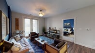 Located at 2785 Polo Club Blvd in Lexington, Kentucky, this single-floor residence offers a thoughtfully designed layout with a bold, contemporary aesthetic throughout. The open-concept kitchen and living area serves as the heart of the home, featuring dark cabinetry, white quartz countertops, stainless steel appliances including a refrigerator, range, microwave, and dishwasher, all set against a striking cobalt blue accent wall. Pendant lighting illuminates the kitchen peninsula, which flows naturally into the living room. The living area is finished with rich hardwood-style flooring and direct access to a private exterior door that invites natural light. The primary bedroom is appointed with plush carpeting and a bold olive-gold accent wall that creates a warm, cozy ambiance. It connects to a well-appointed en-suite bathroom featuring a dual-sink vanity with dark cabinetry, white countertops, and broad mirror lighting. A generously sized walk-in closet with wire shelving provides ample storage. A second bedroom mirrors the comfortable styling of the primary, with carpet flooring and natural light from large windows. The second bathroom includes a single-sink vanity with matching dark cabinetry and a shower-tub combination, maintaining the cohesive design language found throughout this stylish Lexington residence.