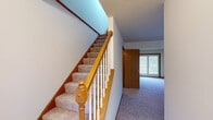 This three-floor residential property offers a functional and practical layout across its levels. The main floor features a galley-style kitchen equipped with white cabinetry accented by warm wood trim, tile flooring, a double sink, and a window that brings in natural light. A carpeted hallway on the main level leads past a staircase with a classic wood banister and white spindles, with sliding glass doors providing access to the outdoors.

The upper floor houses multiple carpeted bedrooms, each finished with neutral tones, wood baseboards, and natural light from double-hung windows. Bedrooms include closets with wood-trimmed doors, offering ample storage. A full bathroom on this level is fitted with tile flooring, a tub-shower combination, a vanity with a large mirror, and clean, neutral finishes throughout.

The lower level includes an attached garage with a concrete floor, block walls, and an automatic door opener, providing convenient vehicle storage. The unfinished basement level houses the mechanical systems, including a furnace and water heater, along with a utility sink and open ceiling that reveals the structural elements. This versatile lower space offers strong potential for future finishing or additional storage use.