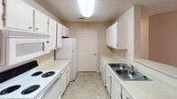 Located at 116 Amelia Forest Ln in Columbia, SC, this single-floor residence offers a straightforward and functional layout designed for comfortable everyday living. The galley-style kitchen is well-appointed with white cabinetry, ample counter space, a double stainless steel sink, and white appliances including a range, refrigerator, and built-in microwave. A dedicated door within the kitchen provides convenient access, and tile flooring adds durability to the space. The kitchen opens to a combined living and dining area featuring a breakfast bar peninsula, neutral carpet flooring, and a textured ceiling. Natural light filters in through windows, and a ceiling fan provides air circulation throughout the living space, which also includes a door leading to the exterior. The bedrooms are carpeted and each equipped with ceiling fans and windows dressed with blinds, offering comfortable, well-lit retreats. The bathrooms feature tile flooring, vanity cabinetry with countertops, and a full tub-shower combination with chrome fixtures. Throughout the home, a consistent neutral color palette, textured ceilings, and clean white trim create a cohesive and move-in-ready atmosphere.