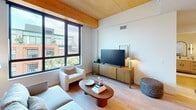 Located at 10 S Paterson St, Unit 621 in Madison, WI, this 870-square-foot apartment offers 2 bedrooms and 2 bathrooms across a single, well-organized floor. The living room is a standout space, featuring striking exposed wood beam ceilings, light hardwood flooring, and large floor-to-ceiling windows that flood the room with natural light and frame views of the surrounding cityscape. The kitchen is outfitted with light wood cabinetry, white quartz countertops, stainless steel appliances including a full-size refrigerator and electric range, recessed lighting, and pendant fixtures over the counter. Both bathrooms are finished in a clean, modern aesthetic with light wood vanities, white quartz surfaces, black hardware accents, arched mirrors, and a tub-shower combination. The primary bedroom spans 150 square feet and features large windows with city views and exposed wood beam detailing. The secondary bedroom is bright and comfortable with plush carpeting. A dedicated walk-in closet features a full organizational system with wood shelving, hanging rods, and pull-out drawers. Hardwood flooring runs throughout the main living areas, complemented by a neutral color palette that reinforces the home's contemporary, minimalist character.