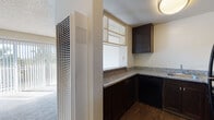 Located at 2493 Lancaster Dr in Richmond, California, this single-floor unit offers a practical and well-appointed layout. The living area is a welcoming, light-filled space featuring plush carpeting and a large sliding glass door dressed with vertical blinds, which allows generous natural light to pour in and provides a view of the surrounding greenery. A textured ceiling adds a classic finishing touch throughout.

The kitchen is efficiently designed with rich, dark espresso cabinetry, granite-look countertops, a stainless steel sink, and black appliances including a gas range and over-the-range microwave. An open pass-through with built-in shelving connects the kitchen to the living area, enhancing the sense of openness and providing convenient display or storage space. A tall HVAC unit is integrated near the kitchen-living transition for year-round climate control.

The bedroom features soft carpeting and a spacious sliding-door closet, offering ample storage. The bathroom is well-equipped with a granite-topped vanity featuring dark cabinetry and chrome fixtures, a large mirror, a combined tub and shower, and durable wood-style flooring that extends throughout the wet areas. Overall, the unit presents a clean, functional interior with consistent finishes that create a cohesive and comfortable living environment.