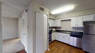 Located at 100 Trails Cir in Nashville, TN, this single-floor unit offers a well-organized and functional layout throughout. The kitchen is a standout feature, equipped with stainless steel appliances including a refrigerator, range, and dishwasher, all complemented by crisp white cabinetry with scalloped detailing and dark granite-style countertops. Hardwood-style flooring runs through the kitchen and living areas, adding warmth and a cohesive aesthetic. The living area is bright and open, benefiting from a large sliding glass door that leads to an outdoor balcony, allowing generous natural light to fill the space. The bedroom features plush carpeting, neutral-toned walls, and a window that brings in additional natural light, creating a calm and restful environment. A generously sized walk-in closet accompanies the bedroom, outfitted with multiple shelving rods along two walls and hardwood-style flooring, providing ample organized storage. The bathroom includes a vanity with dark granite-style countertops, a white undermount sink, chrome fixtures, and a large mirror that enhances the sense of space. Throughout, textured ceilings and neutral wall tones create a consistent, understated backdrop suited to a variety of interior styles.