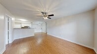 This single-floor residence offers a clean, functional layout designed for comfortable everyday living. The open-concept living and dining area is finished with plush neutral carpeting and features a ceiling fan with integrated lighting, creating a bright and airy atmosphere. A large window near the front entry allows natural light to fill the space, further enhancing the welcoming feel upon arrival.

The kitchen is efficiently designed with white cabinetry, a contrasting suite of black appliances including a refrigerator, range, and built-in microwave, and a peninsula counter with a modern sink — ideal for both meal prep and casual dining. Warm hardwood-style flooring flows throughout the kitchen and dining transition areas, adding visual continuity and easy maintenance.

The bedrooms are carpeted for comfort and offer neutral wall tones, providing a versatile canvas for personalization. The primary bathroom features a wide vanity with a white countertop, a large mirror, and hardwood-style flooring, with a separate water closet for added privacy. A secondary full bathroom includes a tiled shower-tub combination with clean white finishes and chrome fixtures.

Overall, the space presents a cohesive, neutral aesthetic with practical finishes throughout, making it a functional and move-in ready home.