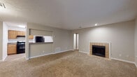 This single-story unit at Belmont Crossing in Riverdale, Georgia, offers a practical and comfortable layout across two bedrooms and two full bathrooms. The spacious living area is anchored by a tile-surround fireplace and features neutral-toned carpet, textured ceilings, and generous wall space. A pass-through opening connects the living area to the kitchen, which is equipped with warm wood cabinetry, dark granite-style countertops, and black appliances including a refrigerator and dishwasher. Wood-look flooring runs through the kitchen and entry areas, adding durability and visual contrast to the carpeted living and bedroom spaces.

A sun-filled flex space off the main living area features large windows on multiple walls, a ceiling fan, and wood-look flooring, offering versatile use as a dining room or sitting area. Both bedrooms are carpeted with textured ceilings and windows providing natural light. Each full bathroom includes a tub/shower combination, with one bathroom featuring warm wood cabinetry and a granite-style vanity top. A dedicated laundry area accommodates a full-size washer and dryer with overhead wire shelving for storage.