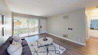Located at 949 East St, Unit 406 in Lafayette, CA, this one-bedroom, one-bathroom unit offers a thoughtfully designed single-level layout. The living room serves as the heart of the space, featuring hardwood-style flooring, neutral gray walls, and a large sliding glass door that floods the room with natural light and provides direct access to an outdoor area with views of surrounding greenery. The open sightlines between the living area and bedroom enhance the sense of spaciousness throughout.

The galley-style kitchen is well-appointed with white shaker cabinetry, dark countertops, stainless steel appliances including an electric range with overhead ventilation, and ample storage via floor-to-ceiling cabinetry. Light wood-tone flooring ties the kitchen seamlessly to the rest of the unit.

The bedroom features soft carpeting, a wide window framing leafy outdoor views, and a calm, neutral color palette that creates a restful environment. The bathroom is cleanly finished with a white vanity with dark countertop, a large wall mirror, wood-look tile flooring, and a tub-shower combination with a window for natural light. The overall design of the unit is clean and modern, with consistent finishes throughout.
