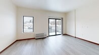 Located at 155 Gramsie Rd in Shoreview, MN, this one-bedroom, one-bathroom unit offers a thoughtfully designed single-floor layout with efficient use of space throughout. Light wood-tone flooring runs continuously across the unit, complementing the clean white walls and recessed lighting that brighten the interior.

The combined kitchen and living area forms the heart of the unit. The kitchen is well-equipped with warm wood cabinetry, stainless steel appliances including a range, dishwasher, and refrigerator, and a double-basin sink with ample counter space. The adjacent living area is open and airy, featuring a sliding glass door that leads to a private balcony, flooding the space with natural light and offering views of the surrounding neighborhood. A wall-mounted HVAC unit ensures year-round comfort.

A hallway with recessed lighting connects the living space to the private bedroom, bathroom, closet, and laundry areas. The bedroom is a cozy, functional retreat. The bathroom is clean and straightforward, featuring a full soaking tub with shower, a wood-vanity, and tile flooring. Sliding barn-style doors add a modern design touch throughout the unit. A dedicated laundry area and closet provide practical storage and convenience within the home.