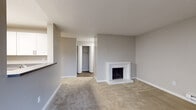 This single-floor residence offers a thoughtfully designed layout with a blend of comfort and functionality. The open living area is anchored by a white brick fireplace, adding a classic focal point to the space, and is finished with neutral-toned carpet throughout. A pass-through opening connects the living area to the kitchen, enhancing the sense of openness. Sliding glass doors lead to a private balcony that overlooks lush, tree-lined surroundings, filling the space with natural light.

The kitchen is equipped with stainless steel appliances, including a refrigerator and dishwasher, complemented by white cabinetry, gray countertops, and wood-look flooring that adds warmth and durability. A double sink and ample cabinet storage make the kitchen both practical and attractive.

The bedrooms are generously sized, carpeted, and feature neutral gray walls with baseboard heating. One bedroom includes a large closet with bifold doors, while another offers direct access to a hallway. The bathrooms are finished with wood-look flooring, white cabinetry, gray countertops, and a full tub-shower combination. Textured ceilings are present throughout, and baseboard heating provides consistent comfort across the residence.