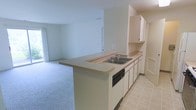 This single-floor, 1-bedroom, 1-bathroom unit features a practical and efficient layout designed to maximize the available living space. The open-concept design seamlessly connects the kitchen and living area, creating a cohesive and airy feel throughout the main living space.

The kitchen is equipped with a gas range, a double-basin sink, a dishwasher, and ample white cabinetry providing generous storage. A peninsula countertop extends into the living area, offering additional workspace and serving as a natural divider between the kitchen and living room. The kitchen floor is finished with light-toned tile, while the adjoining living area features wall-to-wall carpeting that lends a warm and comfortable feel.

The living space is bright and open, with neutral-toned walls that provide a versatile backdrop for a variety of interior styles. Overhead lighting fixtures are installed throughout, ensuring consistent illumination across all areas. The unit's clean, understated finishes and efficient use of space make it a straightforward and functional home suitable for individuals or couples seeking a well-organized living environment.