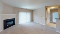 Located on Apple Harvest Circle in Germantown, Maryland, this single-floor residence offers a well-organized and functional layout with comfortable living spaces throughout. The open-concept kitchen is a standout feature, showcasing warm honey-toned wood cabinetry, dark granite countertops, hardwood flooring, and a full suite of stainless steel appliances including a gas range, over-the-range microwave, and refrigerator. The kitchen connects seamlessly to the main living area, which is generously sized and finished with plush wall-to-wall carpeting. The living room features a classic fireplace and a large sliding glass door that fills the space with natural light and provides outdoor access. The entryway transitions from hardwood flooring to carpet and is served by pendant and flush-mount ceiling lighting. The bedroom is well-proportioned, featuring a large window with outdoor views, soft carpeting, and an impressive walk-in closet alongside additional closet space—ideal for storage needs. The bathroom is cleanly appointed with tile flooring, a full tub-shower combination with a curved curtain rod, and neutral warm-toned walls throughout. The overall palette of soft beiges and warm neutrals lends the home a calm and cohesive ambiance.