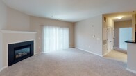 Located on Apple Harvest Circle in Germantown, Maryland, this single-floor residence offers a well-organized and functional layout with comfortable living spaces throughout. The open-concept kitchen is a standout feature, showcasing warm honey-toned wood cabinetry, dark granite countertops, hardwood flooring, and a full suite of stainless steel appliances including a gas range, over-the-range microwave, and refrigerator. The kitchen connects seamlessly to the main living area, which is generously sized and finished with plush wall-to-wall carpeting. The living room features a classic fireplace and a large sliding glass door that fills the space with natural light and provides outdoor access. The entryway transitions from hardwood flooring to carpet and is served by pendant and flush-mount ceiling lighting. The bedroom is well-proportioned, featuring a large window with outdoor views, soft carpeting, and an impressive walk-in closet alongside additional closet space—ideal for storage needs. The bathroom is cleanly appointed with tile flooring, a full tub-shower combination with a curved curtain rod, and neutral warm-toned walls throughout. The overall palette of soft beiges and warm neutrals lends the home a calm and cohesive ambiance.