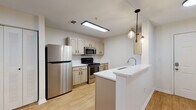 This single-floor residence offers a thoughtfully designed layout that balances functionality and comfort throughout its living spaces. The kitchen serves as a central highlight, featuring cream-toned cabinetry with updated hardware, stainless steel appliances including a full-size refrigerator and gas range, a built-in microwave, and white quartz countertops. A peninsula with an undermount sink and pendant lighting adds both workspace and visual appeal, while light wood-look flooring ties the kitchen seamlessly into the surrounding areas. Adjacent storage with louvered bifold doors provides convenient pantry or closet space near the kitchen.

The living area is bright and open, finished with warm wood-look flooring and a ceiling fan for year-round comfort. French doors with blinds lead to an outdoor access point, allowing natural light to filter into the space. Additional rooms include well-sized bedrooms with plush carpeting, ceiling fans, and closets with built-in shelving for organized storage. The bathroom is cleanly appointed with a tub-shower combination accented by classic tile detailing, a single-sink vanity with quartz countertop, framed mirror, and cabinetry for storage. Throughout the space, a neutral color palette and consistent finishes create a cohesive and move-in ready environment.