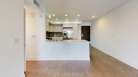 Located at 928 N Oxford Ave, Unit 504 in Los Angeles, this thoughtfully designed residence offers a clean, contemporary aesthetic throughout. The open-concept living and dining area is expansive and bright, featuring light hardwood-style flooring, recessed lighting, and a sliding glass door that opens to a private balcony with neighborhood views — an ideal setting for enjoying the Southern California atmosphere.

The kitchen is a standout feature, showcasing light wood cabinetry, a subway tile backsplash, white quartz countertops, stainless steel appliances including a gas range, microwave, and refrigerator, and a peninsula that provides both prep space and a natural division between the kitchen and living area.

The bedrooms are generously sized, each with large windows that invite abundant natural light and offer views of the surrounding neighborhood, including palm trees and mature greenery. The hardwood-style floors extend throughout, maintaining a cohesive design.

The unit includes multiple bathrooms, each finished with tile flooring and light wood cabinetry. One bathroom features a glass-enclosed soaking tub and shower combination, while another offers a walk-in glass shower with chrome fixtures and built-in shelving — providing both style and functionality throughout.