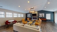 Located at 3500 Beaver Place Rd in Lexington, KY, this single-floor community clubhouse offers a thoughtfully designed gathering space with a welcoming blend of modern and transitional aesthetics. The grand entrance foyer greets visitors with soaring vaulted ceilings, a statement chandelier, and wide-plank hardwood-style flooring that flows throughout the entire space.

The main lounge area serves as the heart of the clubhouse, anchored by a sleek electric fireplace set against a bold dark accent wall clad in stone. Horse-themed artwork pays homage to the Bluegrass region's equestrian heritage. Comfortable seating, including plush sofas and amber wingback chairs arranged around a rustic wood coffee table, creates an inviting atmosphere ideal for relaxed socializing. A pendant light fixture adds a warm, refined touch overhead.

Adjacent to the lounge, an open casual dining area features compact bistro-style tables with bright red chairs, positioned near a bank of natural-light-admitting windows. A dedicated coffee bar with sleek cabinetry, a white quartz countertop, and a Keurig station provides a convenient refreshment spot.

The game room, distinguished by rich teal accent walls and arched windows, centers around a classic billiards table beneath a matching pendant fixture. Glass-paneled doors lead to a private conference or activity room, completing a well-rounded, amenity-rich space designed for community engagement.
