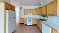 This two-story home offers a thoughtful layout designed for comfortable everyday living. The kitchen is outfitted with warm honey-toned wood cabinetry extending to the upper walls, providing generous storage space. It includes a gas range, a double basin sink, a dishwasher, and a full-size refrigerator, all set on easy-care tile flooring. The open main living area flows naturally from the kitchen and features tile flooring, a ceiling fan, and a staircase leading to the upper level. A separate living room on the upper floor is highlighted by a fireplace with a light wood surround, a ceiling fan, and a window that brings in natural light and outdoor views of surrounding greenery. The bedrooms are carpeted and bright, each benefiting from large windows that frame tree-lined views, creating a calm and airy atmosphere. One bedroom features a walk-in closet, adding practical storage. A dedicated laundry closet on the upper level houses a stacked washer and dryer unit, offering added convenience. Throughout the home, neutral tones, white trim, and clean lines contribute to a cohesive and welcoming aesthetic across both floors.
