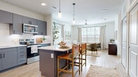 Located in Dripping Springs, TX, this thoughtfully designed one-bedroom, one-bathroom residence offers a well-appointed single-floor layout that maximizes both function and comfort. Light wood-tone flooring flows throughout, complemented by crisp white walls that create a bright, airy ambiance.

The open-concept kitchen and living area serves as the heart of the home. The kitchen features slate-gray cabinetry with matte black hardware, a white quartz countertop, stainless steel appliances, and a central island with bar seating — ideal for casual dining. Pendant lighting and abundant natural light enhance the space. The adjoining living area offers large windows with scenic views of the Texas Hill Country, fitted with wood blinds and linen drapes, and is completed by a ceiling fan overhead.

A dedicated office provides a quiet, functional workspace separate from the main living areas. The spacious bedroom accommodates a large bed comfortably, features a ceiling fan, and enjoys natural light through well-placed windows. The full bathroom offers gray cabinetry, a white vanity top, and a wide mirror with modern black-framed fixtures. Two closets, including a generous walk-in with built-in shelving, provide ample storage. A laundry area and utility room round out this practical and polished residence.