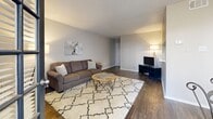 Located at Crystal Springs in Bedford, TX, this one-bedroom, one-bathroom residence offers a thoughtfully designed single-floor layout that maximizes comfort and functionality. The open-concept living, dining, and kitchen area serves as the heart of the home, featuring rich dark hardwood flooring, a textured ceiling, and a tile-surround wood-burning fireplace flanked by built-in shelving. French doors flood the space with natural light and provide a seamless connection to the outdoors, while a pass-through window links the kitchen to the living area for added convenience. The living room offers generous proportions, ideal for both relaxing and entertaining. The bedroom is a comfortable retreat, carpeted for warmth, with a large window that invites natural light and an outdoor view. Multiple closets throughout — including a spacious walk-in with wire shelving — provide exceptional storage for a home of this size. The bathroom features wood-look flooring, a clean white tiled tub-shower combination, and a grab bar for added accessibility. Neutral tones and soft grey walls carry throughout, creating a cohesive and inviting ambiance. With five closets total, this residence stands out for its remarkable storage capacity relative to its scale.