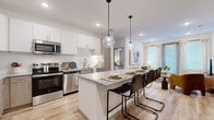 Located in Avondale, Arizona, this well-appointed 2-bedroom, 3-bathroom residence offers a thoughtfully designed single-floor layout with modern finishes and a bright, cohesive aesthetic. The kitchen serves as a true centerpiece, featuring crisp white upper cabinetry paired with warm wood-toned lower cabinets, a classic subway tile backsplash, granite countertops, and a full suite of stainless steel appliances. A spacious granite-topped island with seating for multiple guests flows naturally into the open living area, where light wood-style flooring and large windows fill the space with natural light. The living room is warm and inviting, with neutral tones and generous window treatments. Both bedrooms are well-proportioned and carpeted, each featuring large windows with blinds and ceiling fans. The primary bedroom includes a dedicated closet with built-in shelving and rod systems offering ample storage. The bathrooms are finished with granite vanities, wood-toned cabinetry, large wall mirrors, and light tile flooring. One bathroom features a glass-enclosed walk-in shower with white subway tile walls and mosaic tile flooring. Two dedicated closets provide practical everyday storage throughout the residence.
