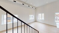 This two-story residence in Philadelphia's 19134 neighborhood offers a thoughtfully designed layout spread across two floors, with the main level providing generous living and kitchen space and the upper level offering a spacious primary bedroom. Light hardwood flooring flows throughout, complementing the clean, modern aesthetic defined by crisp white walls and recessed lighting.

The kitchen is a standout feature, showcasing white shaker cabinetry extending to the ceiling, a quartz waterfall island with an undermount stainless steel sink and matte black faucet, subway tile backsplash, and stainless steel appliances including a French door refrigerator, range, and built-in microwave. Large windows flood the kitchen with natural light and offer views of the surrounding neighborhood.

The main living area is open and airy, with high ceilings, track lighting, and multiple windows that bring in abundant daylight. A striking dark-metal staircase with vertical balusters connects the two floors, adding an architectural focal point.

The primary bedroom is generously proportioned with bright natural light from street-facing windows. Both bathrooms are finished with large-format neutral tile, soaking tubs with shower combinations, and coordinating matte black hardware, maintaining a cohesive and refined aesthetic throughout.