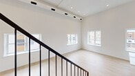 This two-story residence in Philadelphia's 19134 neighborhood offers a thoughtfully designed layout spread across two floors, with the main level providing generous living and kitchen space and the upper level offering a spacious primary bedroom. Light hardwood flooring flows throughout, complementing the clean, modern aesthetic defined by crisp white walls and recessed lighting.

The kitchen is a standout feature, showcasing white shaker cabinetry extending to the ceiling, a quartz waterfall island with an undermount stainless steel sink and matte black faucet, subway tile backsplash, and stainless steel appliances including a French door refrigerator, range, and built-in microwave. Large windows flood the kitchen with natural light and offer views of the surrounding neighborhood.

The main living area is open and airy, with high ceilings, track lighting, and multiple windows that bring in abundant daylight. A striking dark-metal staircase with vertical balusters connects the two floors, adding an architectural focal point.

The primary bedroom is generously proportioned with bright natural light from street-facing windows. Both bathrooms are finished with large-format neutral tile, soaking tubs with shower combinations, and coordinating matte black hardware, maintaining a cohesive and refined aesthetic throughout.