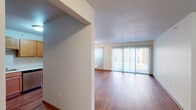 This thoughtfully designed 2-bedroom, 2-bathroom single-floor residence offers a functional and comfortable layout throughout. The combined kitchen and living area serves as the heart of the home, where the living room features warm hardwood-style flooring and floor-to-ceiling vertical blinds covering a large sliding glass door that fills the space with abundant natural light. The kitchen is well-equipped with stainless steel appliances, including an electric range, over-the-range microwave, and dishwasher, complemented by classic wood cabinetry, white countertops, and a double basin sink. Both bedrooms are carpeted and receive natural light through large windows with outdoor views. The primary bedroom is generously sized and includes a dedicated walk-in closet with built-in shelving. The second bedroom features a wood-paneled closet door. The two bathrooms are finished with wood-tone vanities, white countertops, and hardwood-style flooring, one featuring a glass-enclosed shower. A dedicated laundry room houses a full-size top-loading washer and dryer with wire shelving above for added storage. A hallway connects the private spaces of the home, completing a practical and cohesive floor plan.