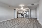 Located at 165 N Hoover St in the heart of Los Angeles, CA, this single-floor unit offers a clean, modern aesthetic throughout. The open-concept living and dining area is finished with light-toned luxury vinyl plank flooring that extends seamlessly across the entire unit, creating a cohesive and contemporary feel. Neutral gray and white walls complement the natural light that filters in through slatted window blinds, offering views of the surrounding neighborhood.

The kitchen is well-appointed with white shaker-style cabinetry, a decorative tile backsplash in a mosaic pattern, light countertops, and stainless steel appliances including a gas range and a side-by-side refrigerator with an ice and water dispenser. A walk-in closet is conveniently situated just off the kitchen area.

The bedrooms are generously proportioned, each featuring the same plank flooring, neutral wall tones, and windows that bring in ample natural light with views of the Los Angeles cityscape. The bathroom is finished with large-format, linear tile surrounding the soaking tub and shower combination, accented by brushed nickel fixtures for a polished look. The overall design emphasizes clean lines, functional layouts, and modern finishes throughout.