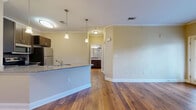 Located at 2900 E North St in Greenville, SC, this one-bedroom, one-bathroom unit offers a well-designed layout across a single floor. Rich hardwood flooring flows throughout the open-concept living and kitchen areas, complemented by crisp crown molding and warm neutral tones that create a clean, cohesive aesthetic.

The kitchen is thoughtfully appointed with dark espresso cabinetry, granite countertops, a tiled backsplash, and a full suite of stainless steel appliances including a refrigerator, range, microwave, and dishwasher. A peninsula with pendant lighting bridges the kitchen and living area, providing additional counter space and an informal dining option.

The living room is bright and open, benefiting from multiple windows with outdoor views of surrounding greenery and access to a private balcony, allowing for ample natural light. The bedroom features plush carpeting, a ceiling fan, its own window and balcony access, and a dedicated walk-in closet with built-in shelving for generous storage. The bathroom continues the refined finishes seen throughout the unit.

A dedicated laundry closet with a stacked washer and dryer adds everyday convenience. This unit combines practical functionality with attractive finishes in a comfortable Greenville location.