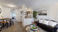 This well-organized single-floor unit offers a practical and functional layout across three distinct areas. The combined kitchen and living room serves as the heart of the space, featuring a carpeted living area with a sliding glass door fitted with vertical blinds that allows natural light to filter in. The kitchen is positioned adjacent to the living space, separated by a partial dividing wall that creates an open-pass-through feel. The kitchen is equipped with a full-size refrigerator, an electric range with overhead ventilation, a dishwasher, a single-basin sink, and ample upper and lower cabinetry finished in a warm brown tone. Wood-look flooring in the kitchen adds a clean contrast to the carpeted living zone. A textured ceiling runs throughout the unit, lending a classic residential character. The bathroom features wood-look flooring, a full-size soaking tub with a shower and curtain rod, a toilet, and a vanity with an integrated sink and countertop. A closet provides dedicated storage space to keep the unit organized. The overall layout is efficient and thoughtfully arranged, making excellent use of the available footprint while maintaining a comfortable and livable atmosphere.